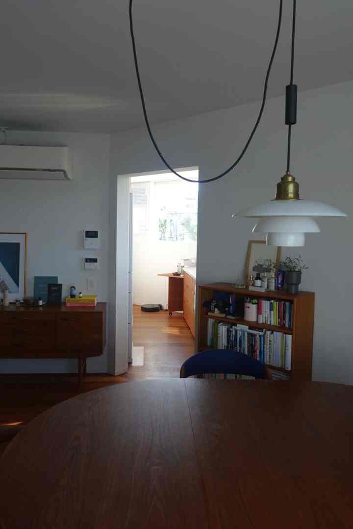 白い壁と木目調の家具が調和したダイニング、ルイス・ポールセンのペンダントライトが中央に配置されたミッドセンチュリーモダンの雰囲気あるインテリア