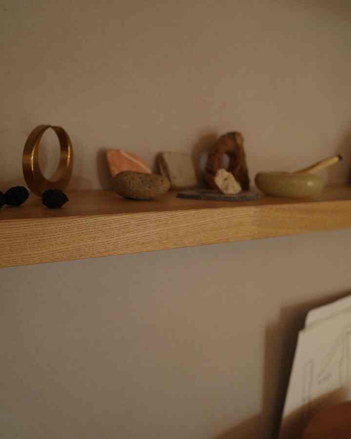 暖かいベージュ色の壁と木目調の棚にオブジェが置かれた雰囲気のあるインテリア
