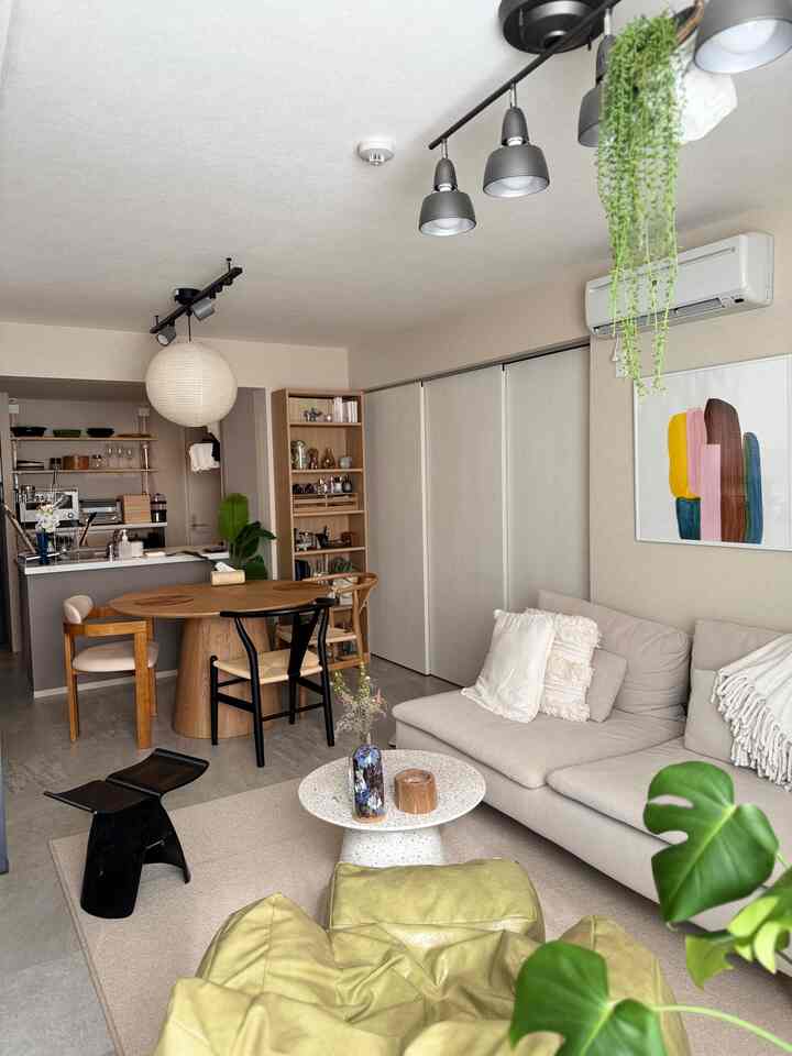 ベージュと木目調が調和したリビング兼ダイニング、ポスターと天井照明が印象的なモダンな空間