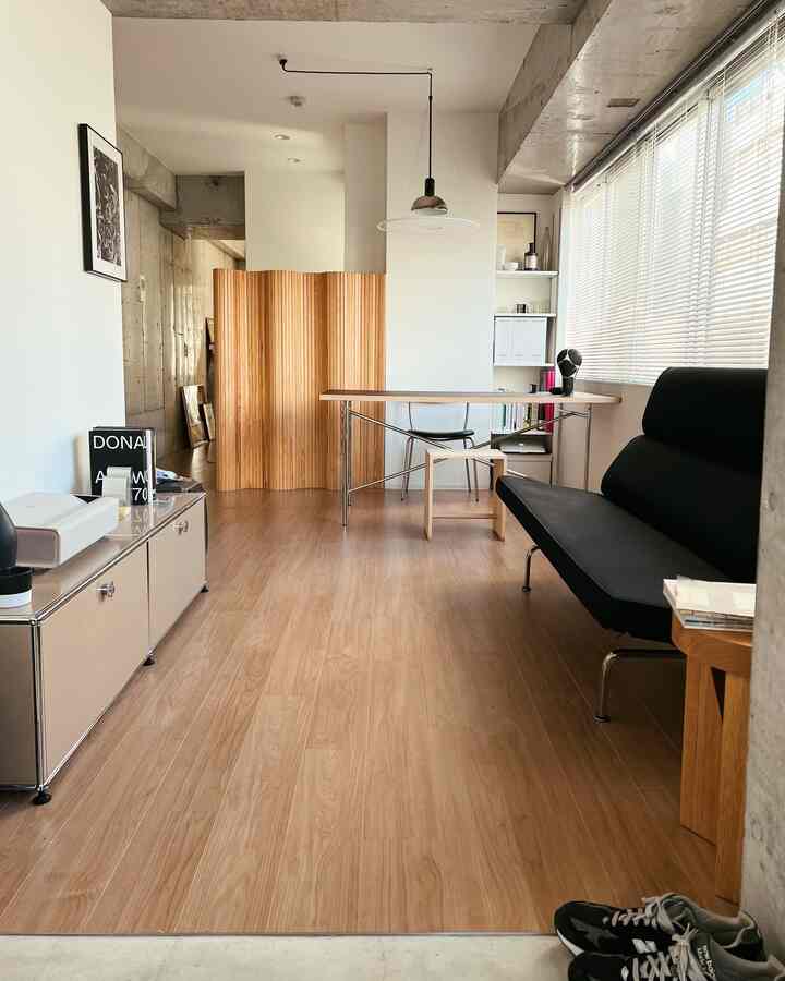 木目調の床とモダンな黒いソファ、ダイニングテーブルが配置された1LDKのリビングダイニングの雰囲気あるインテリア