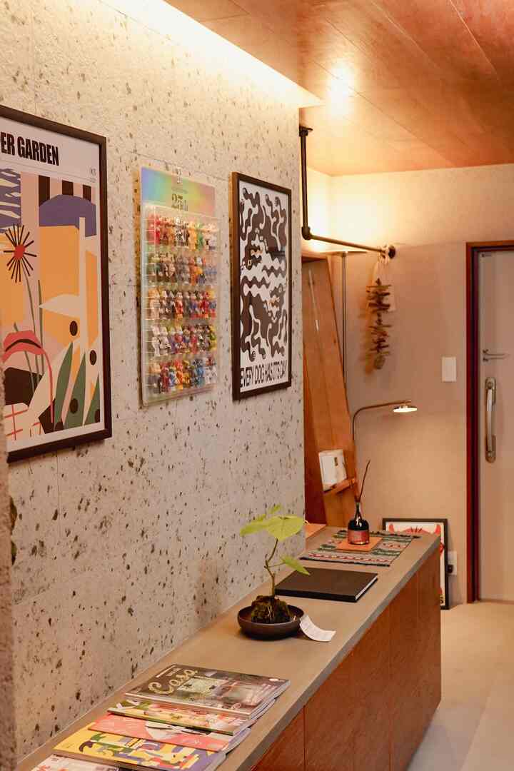 ウッドトーンの天井と収納があるナチュラルな玄関スペース、壁には額装と照明が配置されて温かみのある雰囲気