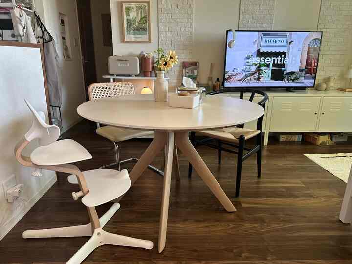 アイボリーと木目調のダイニング、丸テーブルと異なるデザインの椅子が配置された温かみのある空間