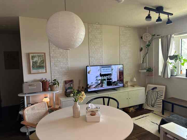 白とナチュラルカラーのキッチンとダイニング、丸いダイニングテーブルと植物が配置されたモダンで落ち着いた雰囲気のインテリア