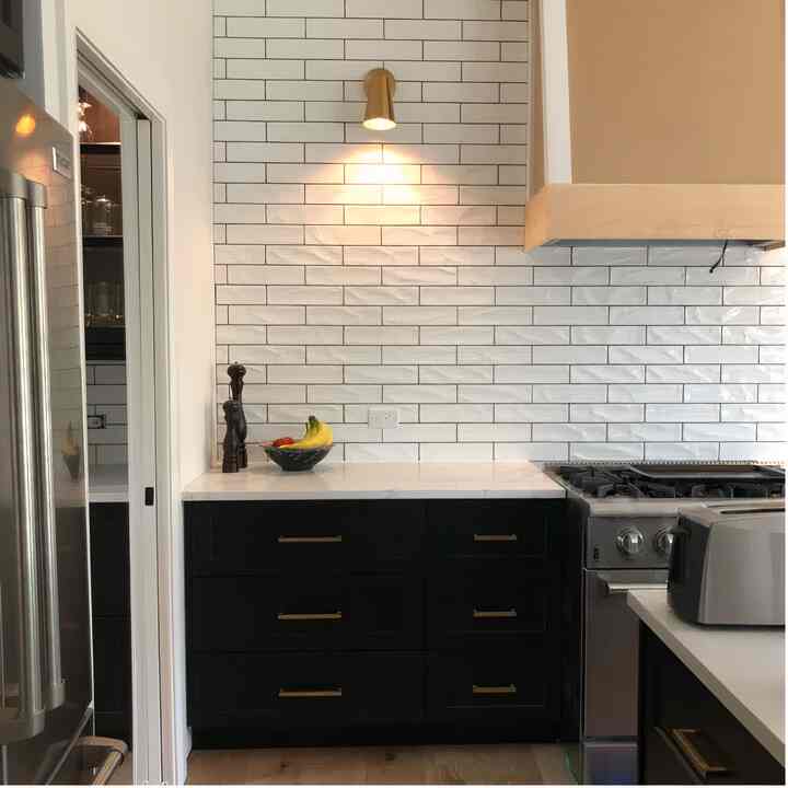 This small kitchen packs a punch! Stylish design and smart lighting, thanks to the sleek light sconce, make it feel spacious. #modernkitchen #kitcheninspo #sleekdesign
