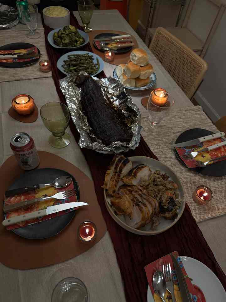 Beige tablecloth and burgundy table runner on dining room table set with food and candles, creating a warm home party atmosphere