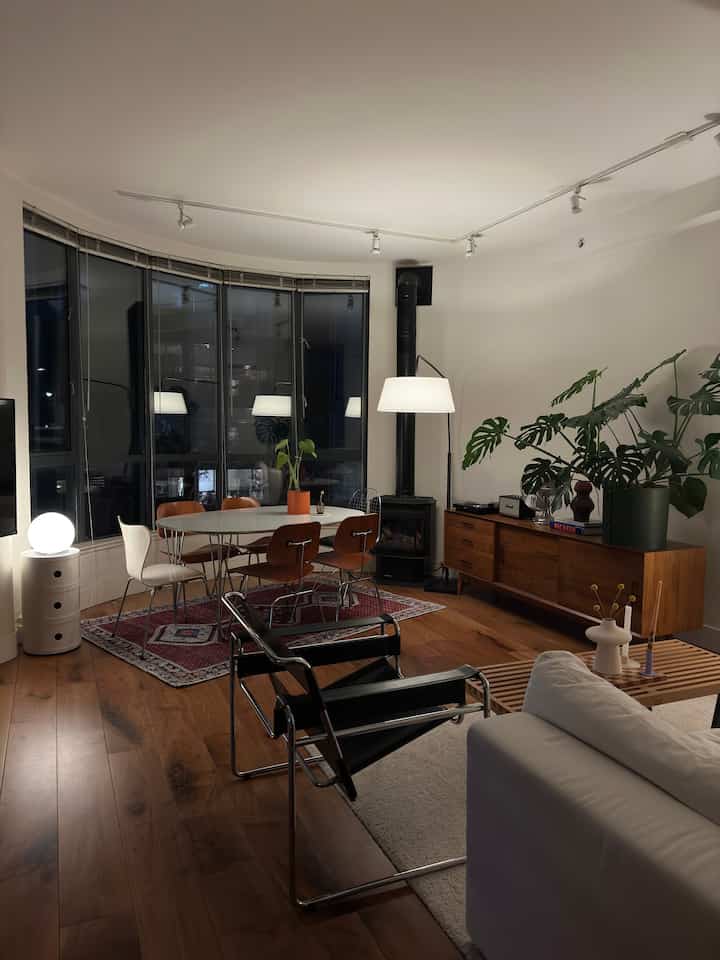 Warm wood tones and white hues define a cozy living and dining room featuring modern, simple furniture