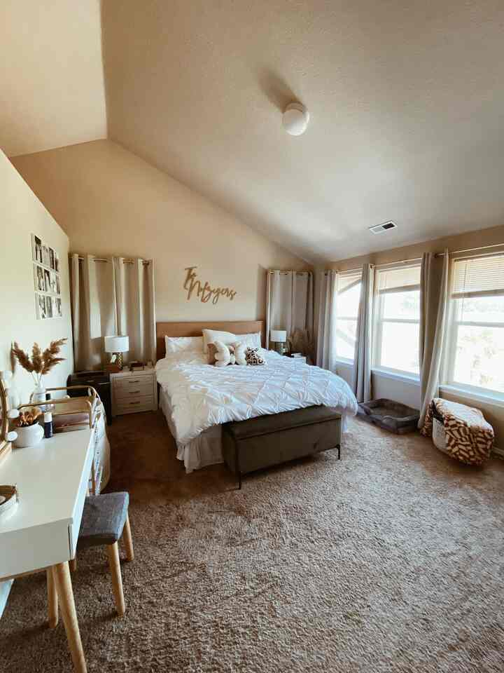 Beige-toned bedroom with white bedding, velvet bench, and natural elements creating a cozy bohemian style atmosphere