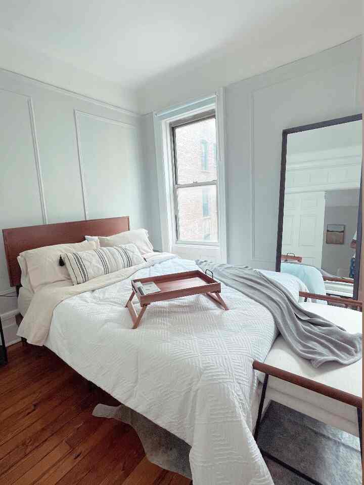 White and wood tone bedroom featuring central bed, nightstand, and serving tray with cozy atmosphere