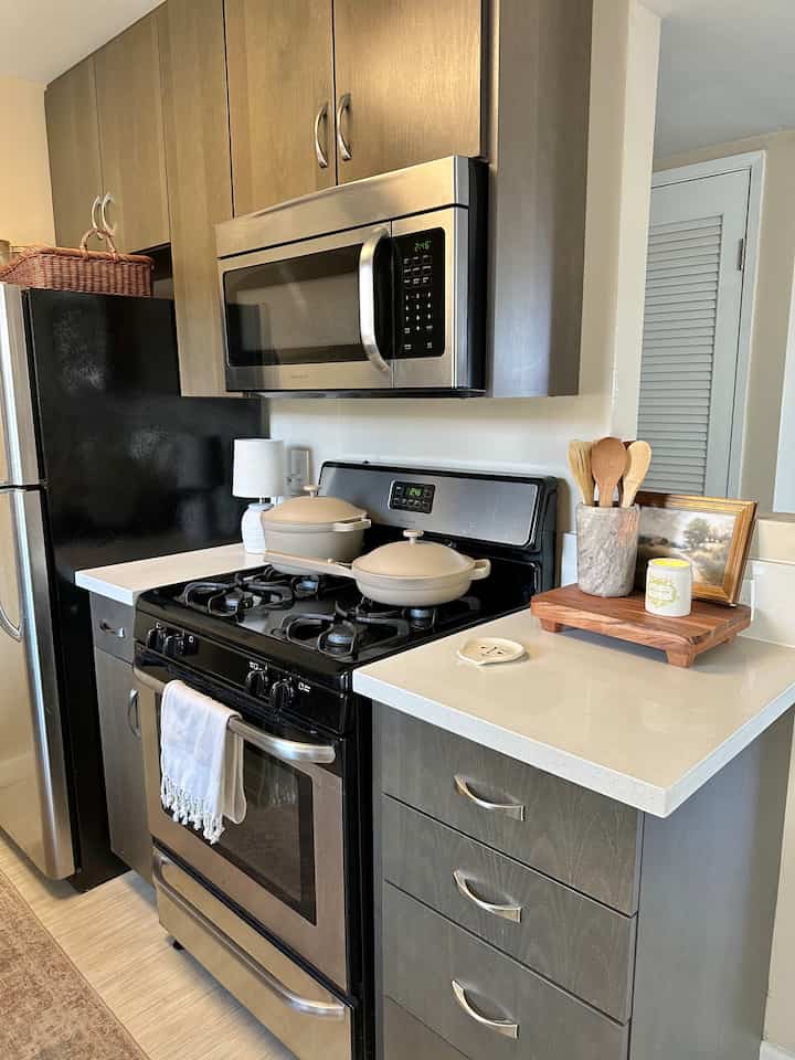 White and gray toned kitchen featuring stainless steel microwave and pots on stove, modern and clean space