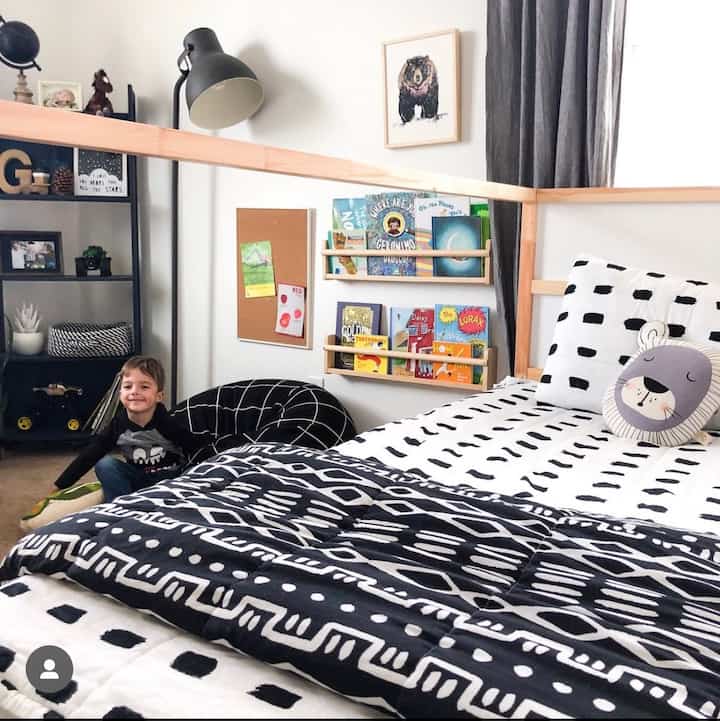 Monotone black and white kids' room featuring a bed, bookshelf, bean bag, and curtains with a cozy atmosphere