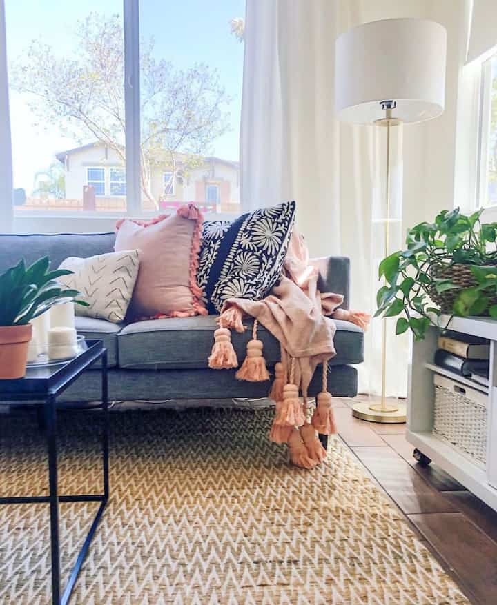 Bright white and gray toned living room featuring a gray sofa with decorative cushions and a natural-toned rug
