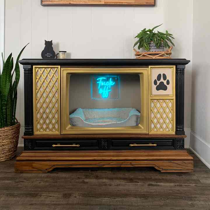 Vintage wood-toned TV stand featuring cat-related decor and a pet bed in a cozy setup