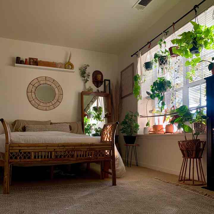 A cozy bedroom with natural wood tones and abundant plants, featuring Bohemian style interior.