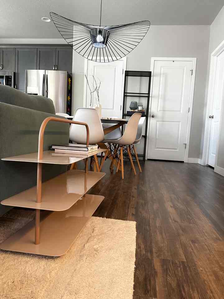 A white and wood-toned living and dining room featuring a modern sofa and dining chairs in a cozy space