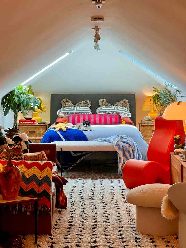 Warm red and blue toned loft bedroom featuring a centrally placed bed with a cat resting comfortably, creating a cozy atmosphere