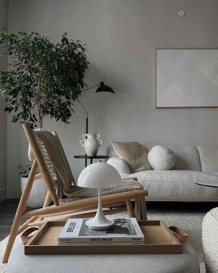 Natural modern toned living room featuring wooden frame armchair and lounge sofa arranged cleanly