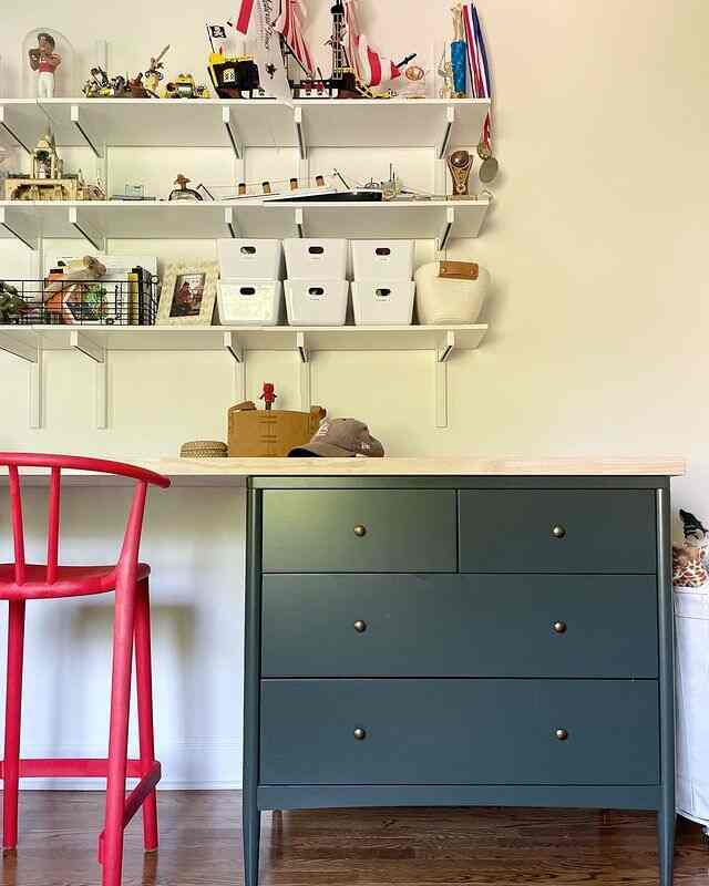 Natural-toned practical home office space featuring a red stool and dark gray dresser with tidy storage