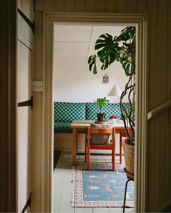 A wood-toned and green dining room featuring a wooden dining table and checkered sofa creating a cozy atmosphere
