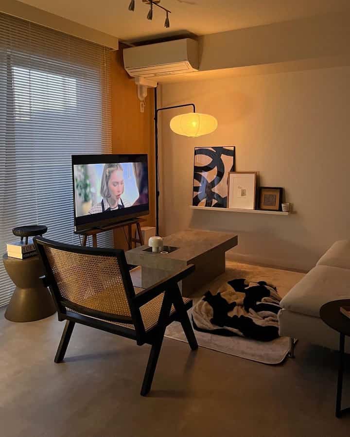 Brown and beige toned living room featuring Pierre Jeanneret armchair and concrete coffee table in a minimal warm space