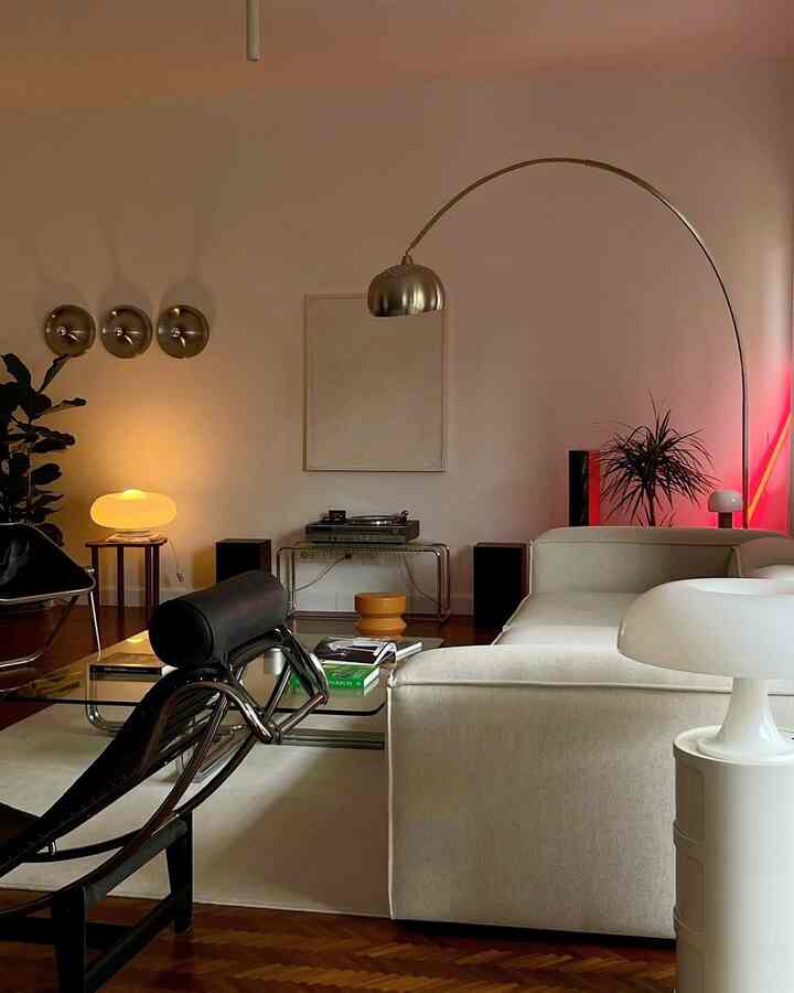 Soft white-toned living room featuring modern sofa and arch floor lamp with a warm, cozy ambiance