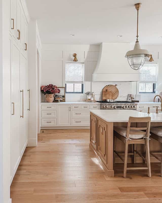 A spacious French country style kitchen in white and wood tones, featuring elegant pendant lighting and a kitchen island