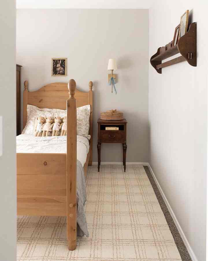 Natural-toned cozy bedroom featuring a wooden bed, small nightstand, wall sconce, and wall-mounted shelf