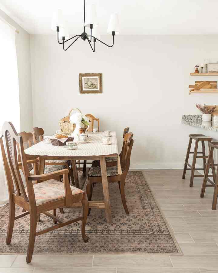 White and brown toned dining room featuring wooden table and chairs with chandelier, creating a warm atmosphere