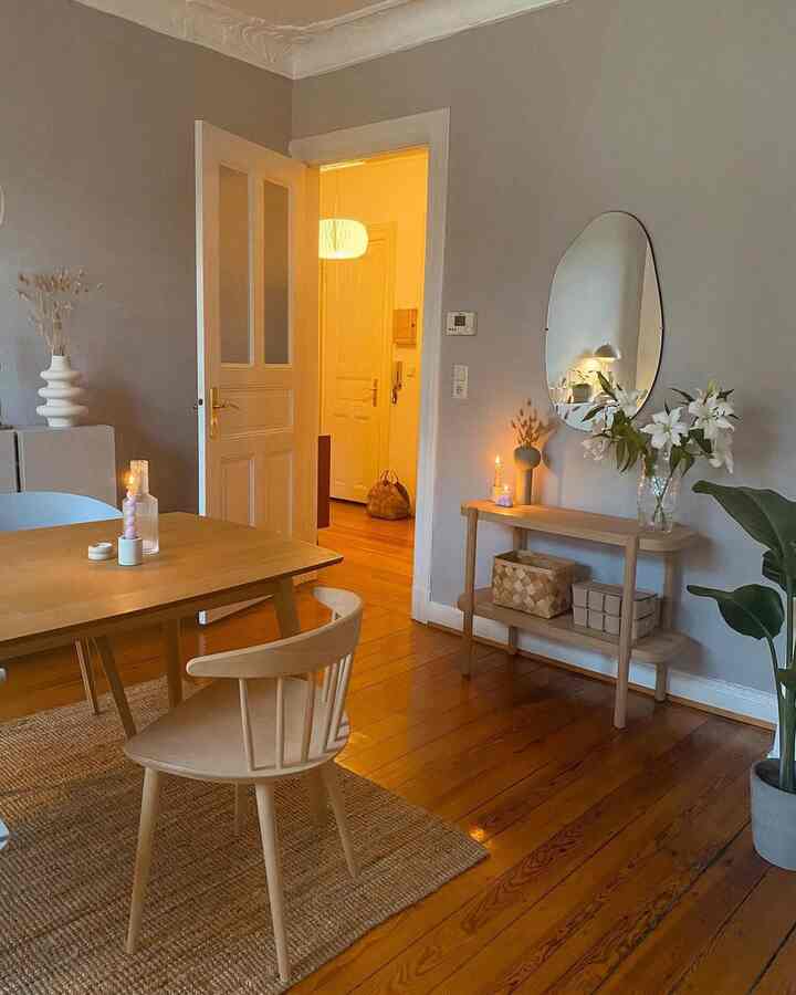 Natural color wood tone dining table and chair with candles and mirror in a cozy dining room space