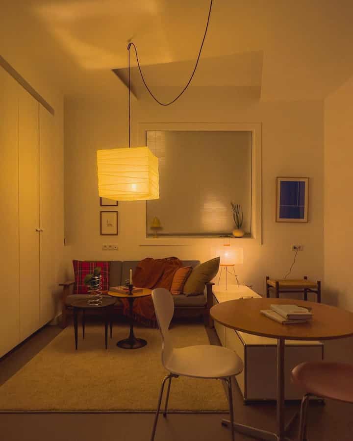 Warm-lit natural modern living room featuring a central sofa and round tables creating a cozy atmosphere