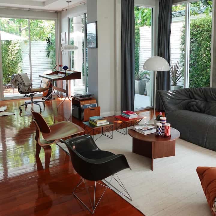 A natural light-filled living room with warm wood tone flooring and mid-century modern furniture pieces
