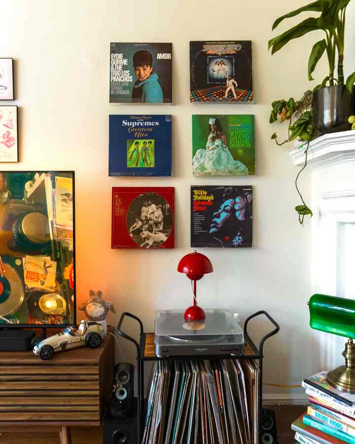 Brown wood tones and red lighting accent a vintage-style living room decorated with posters and vinyl records