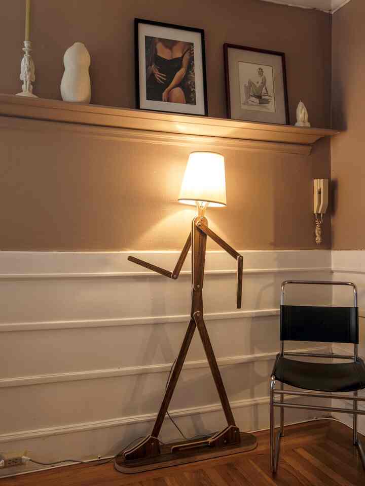 Warm brown-toned dining room with a wooden floor lamp shaped like a stick figure and a black chair, creating a cozy atmosphere
