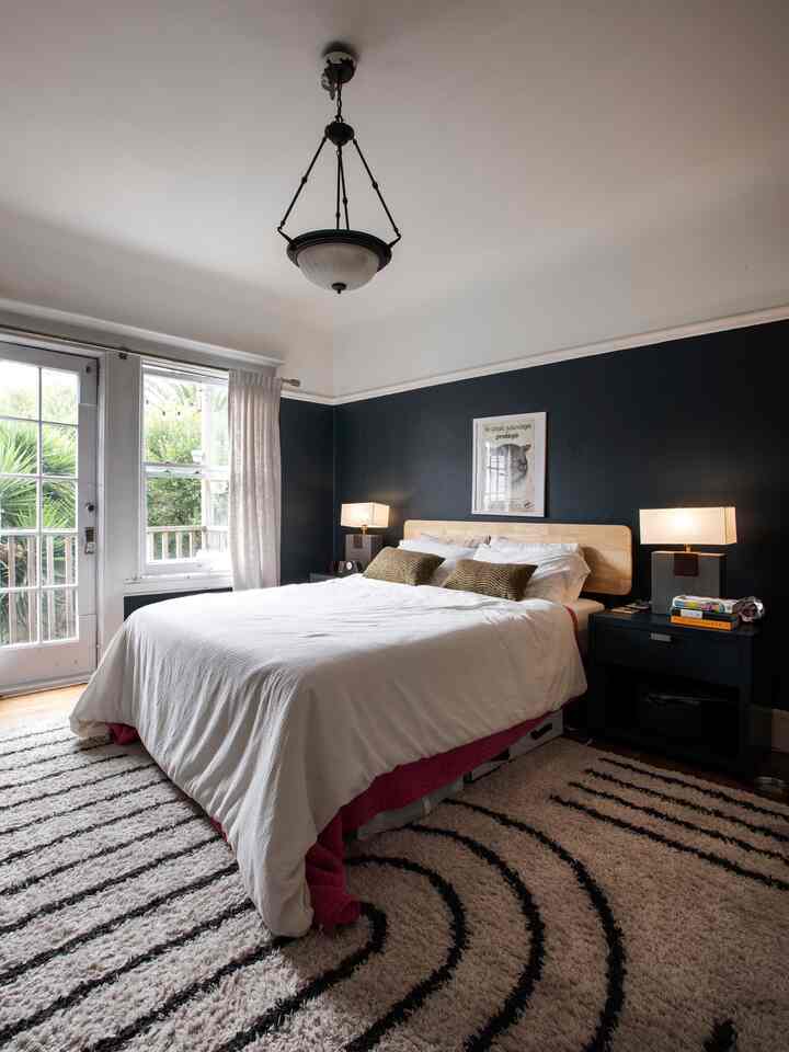 Natural modern bedroom in white and black tones, featuring a large bed, nightstands, and textured rug creating a cozy atmosphere