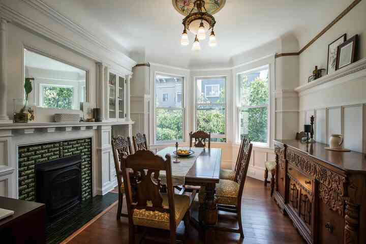 Bright white-walled dining room featuring brown classic wooden furniture and a fireplace basked in natural light