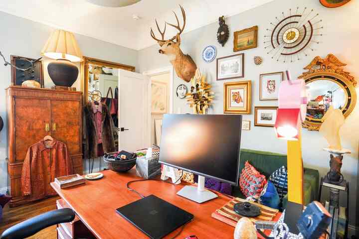 Warm wood tones and vintage-inspired home office with a sofa and eclectic gallery wall creating a cozy living room