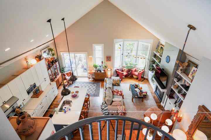Bright warm wood tones with vintage sofa and pendant lights in an open floor plan living room, kitchen, and dining area