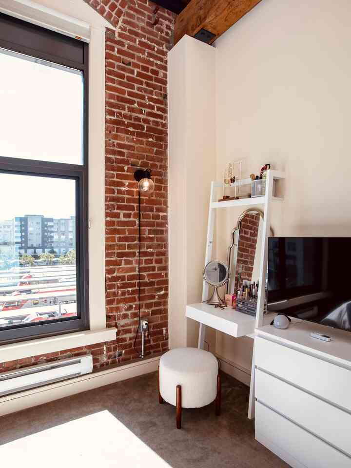 Bright and cozy mid-century modern room with brown brick wall and white furniture