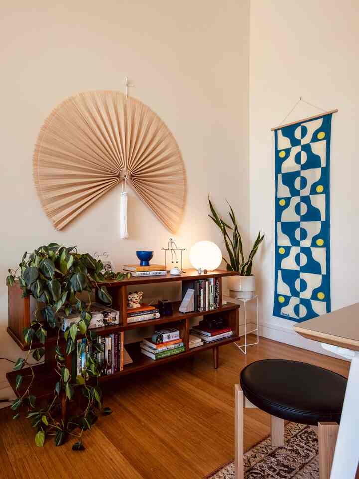 Natural color walls and Mid-Century Modern bookshelf, plants, and table lamp arranged in a calm dining room space