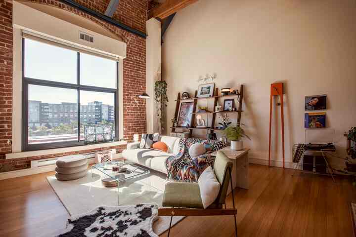 A white and orange toned living room featuring mid-century modern sofa and clock with exposed brick walls creating a warm atmosphere