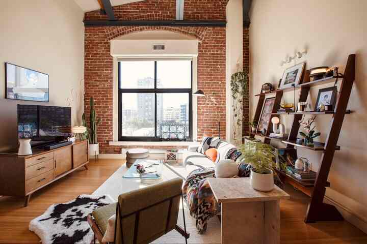 Mid-century modern living room featuring warm wood tones and exposed brick walls, bathed in natural light creating a cozy atmosphere