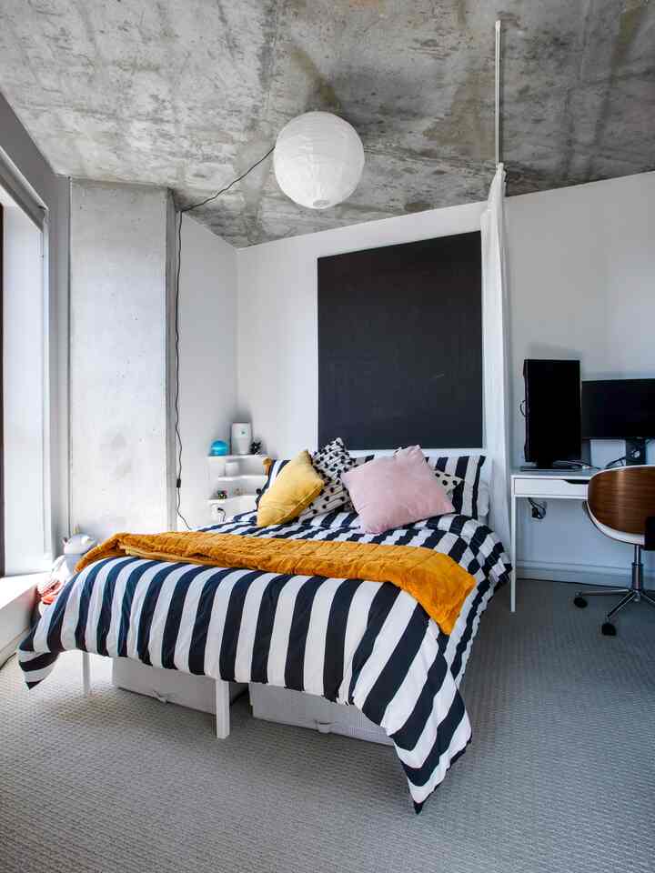 Black and white toned bedroom featuring striped bedding and yellow accents, conveying a modern atmosphere