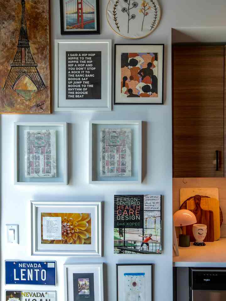 White-walled living room home gallery featuring multiple picture frames and wood tone cabinetry with a simple, modern atmosphere