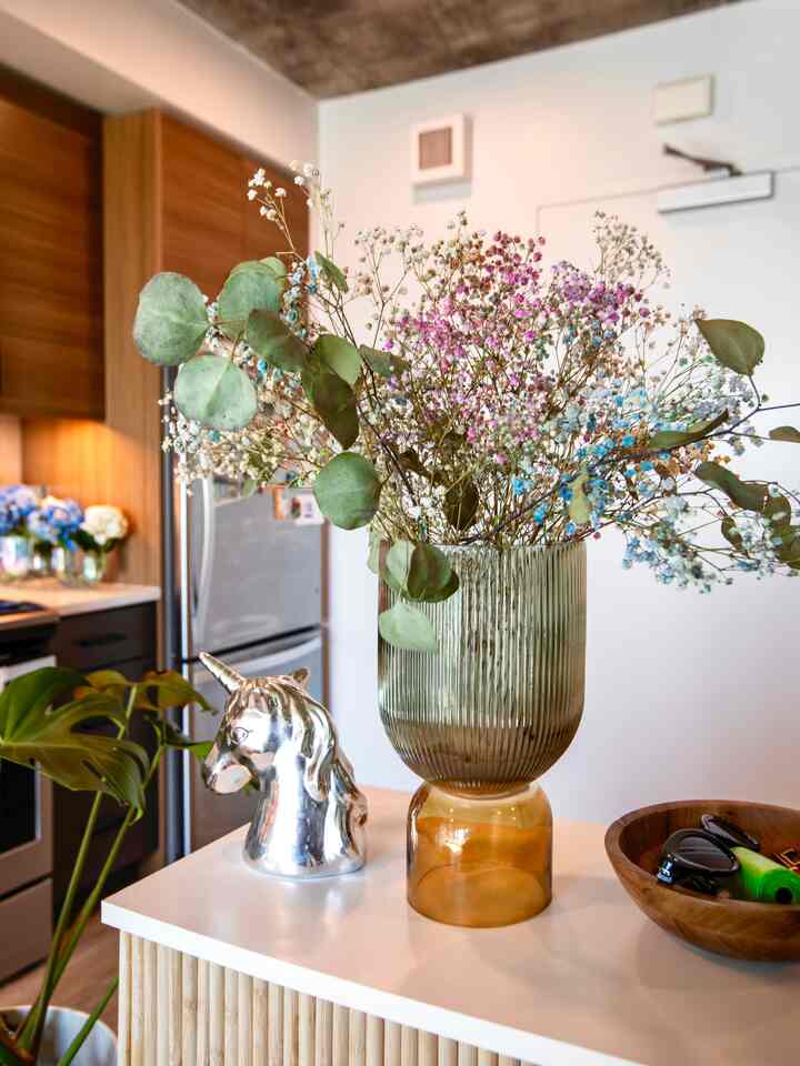 Soft wood tones and white blend in kitchen featuring a central vase with flowers and a silver unicorn figurine, creating a warm atmosphere