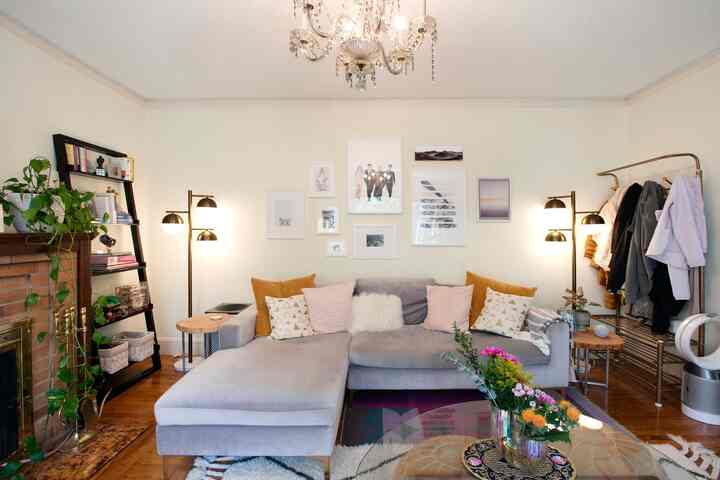 White and gray toned living room featuring a sectional sofa, picture frames, and wood-tone flooring with cozy atmosphere