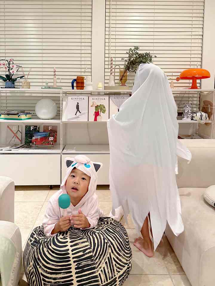 White and black mid-century modern living room with kids in Halloween costumes, depicting a cozy and playful atmosphere