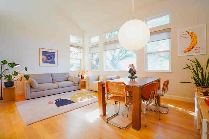 Bright natural wood tone and white living and dining room for two, featuring sofa and armchair in a minimal modern style