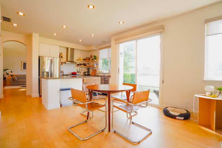 Bright minimal dining room with orange mid-century modern dining chairs around a round wooden table