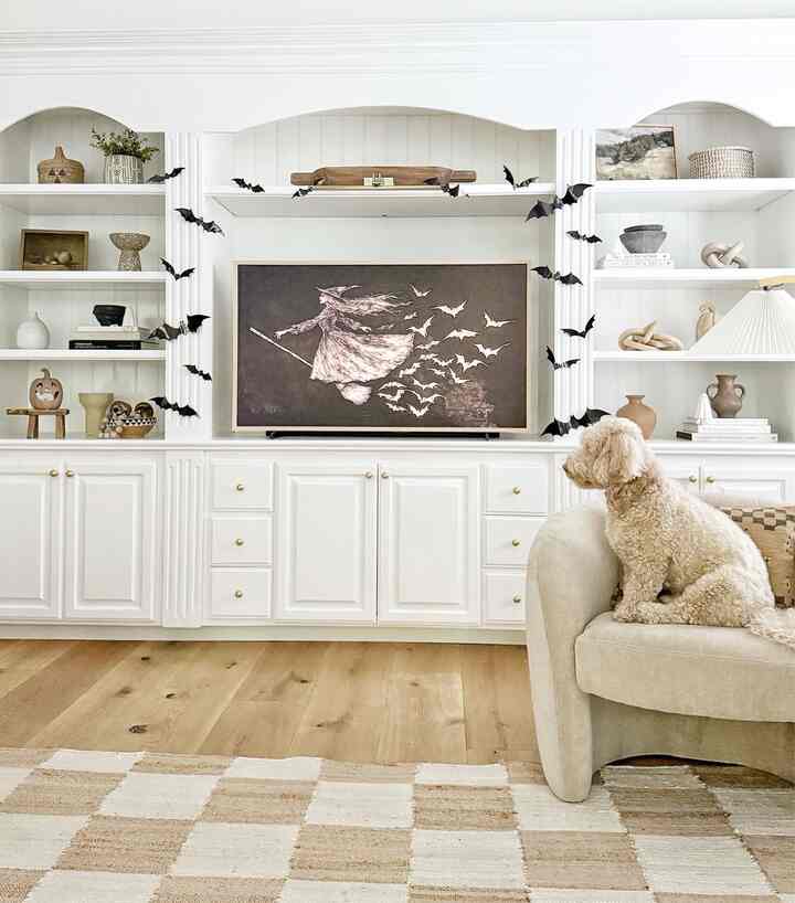 Natural toned classic living room featuring Halloween decor, framed TV art, and cozy seating with a dog
