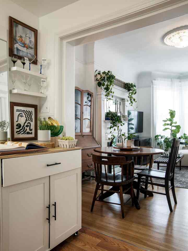 A cozy dining room and living space featuring white backgrounds and wood tone furniture with dining table and chairs