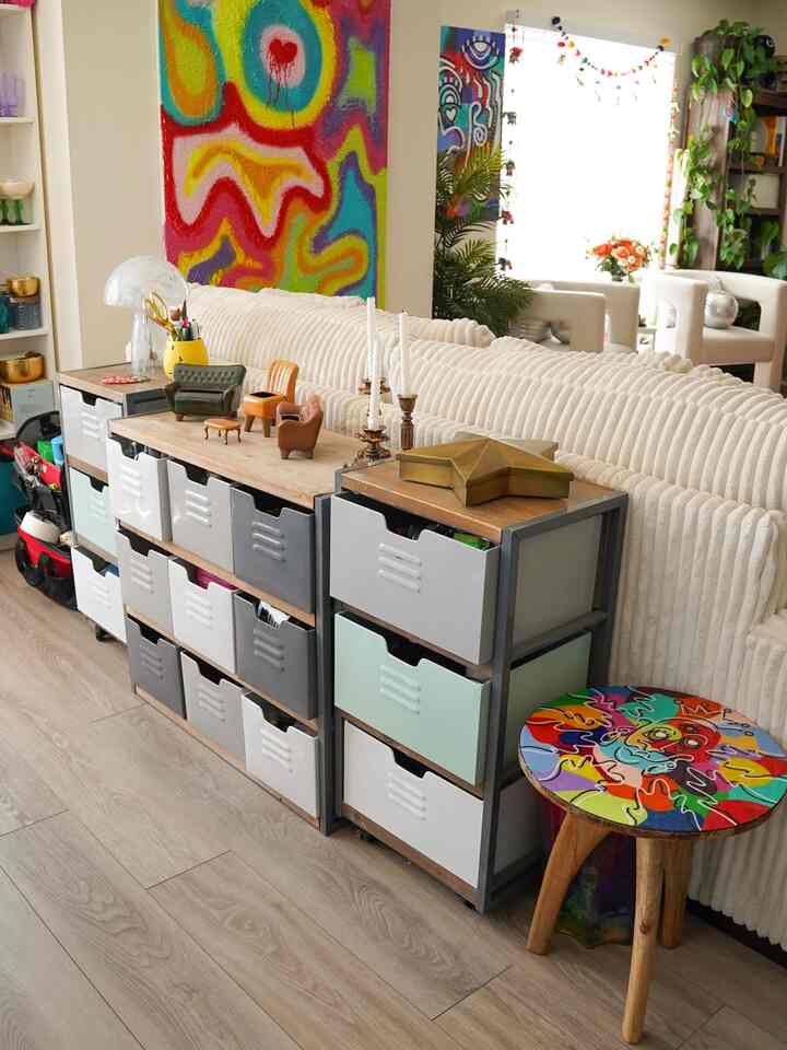 Bright natural-toned living room featuring multi-colored storage bins and a vibrant artistic stool with a cozy, personalized atmosphere